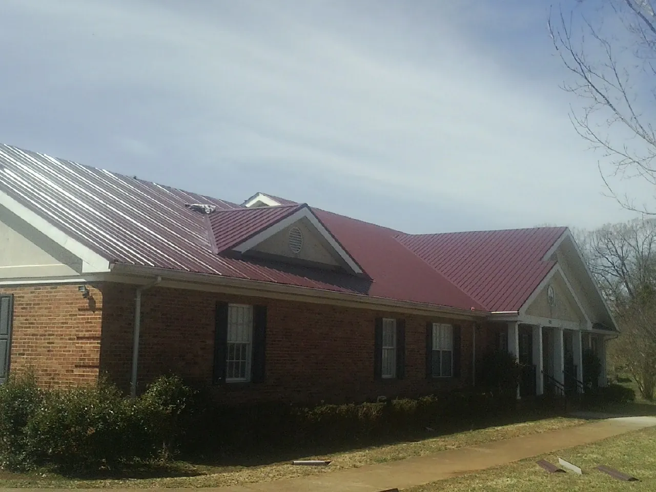 Red metal roof with gabled entries on a long brick building in Columbus